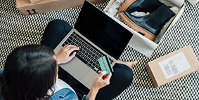 Lady reviewing her credit card with laptop on her lap