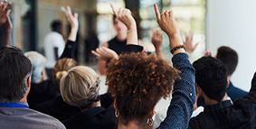 people in auditorium with hands raised