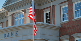 La bandera de los Estados Unidos ondeando frente a una sucursal bancaria